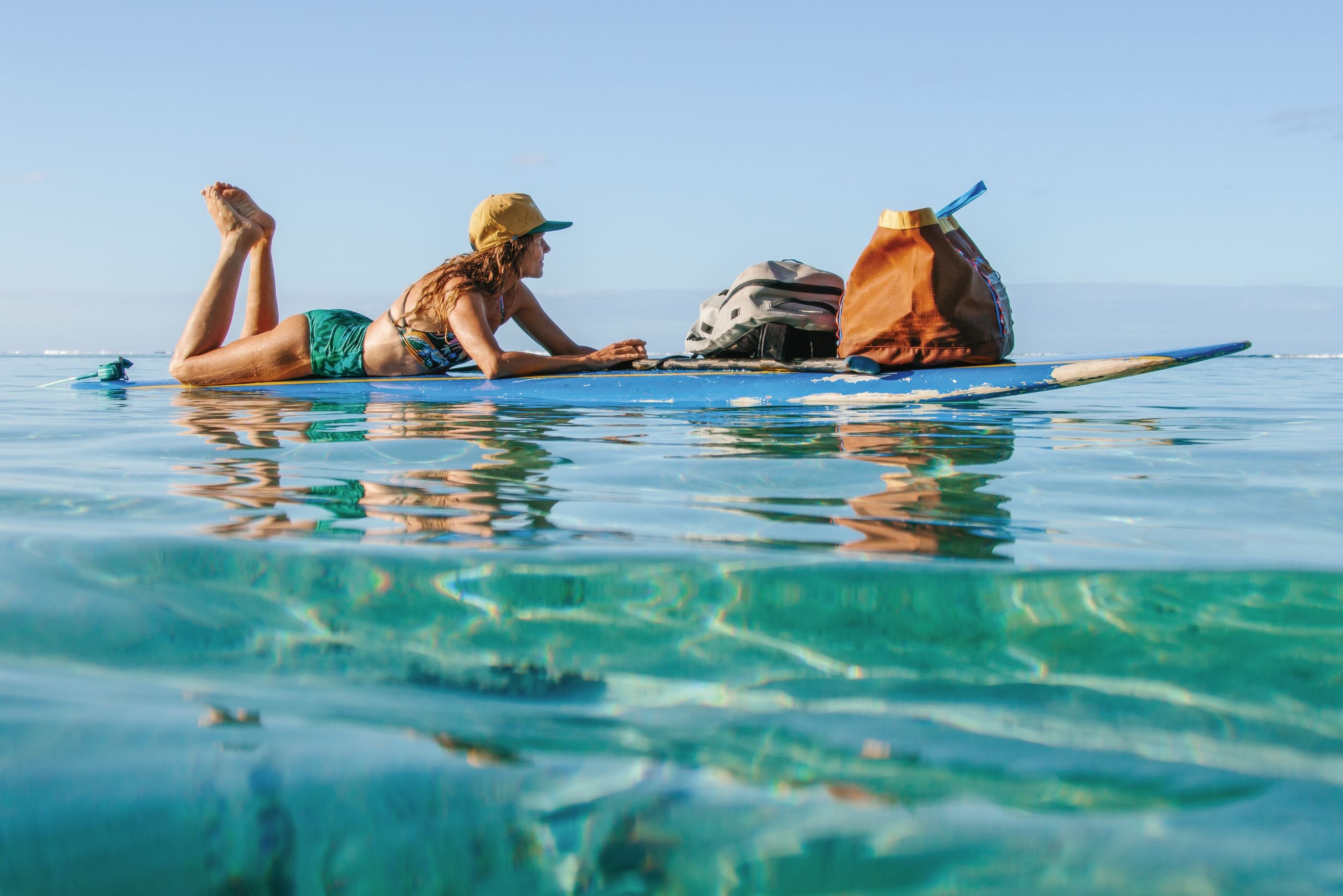 Some folks use the basket on their bike to run errands, others the nose of their longboard. Captain Liz Clark returns to shore after visiting her sailboat Swell. Tahiti.